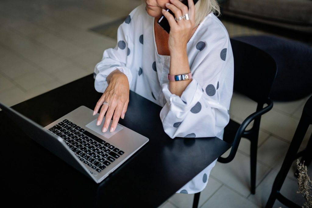 Professional woman multitasking with laptop and phone in modern setting.